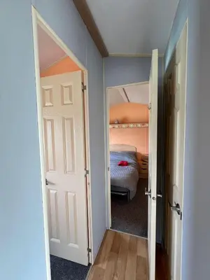 a bedroom with a bed and an open door at Light and Airy 2 Bedroom Mobile Home in Aberystwyth