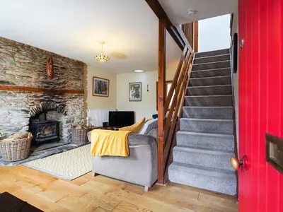 a living room with a stone fireplace and a staircase at Delfryn, Goginan in Aberystwyth