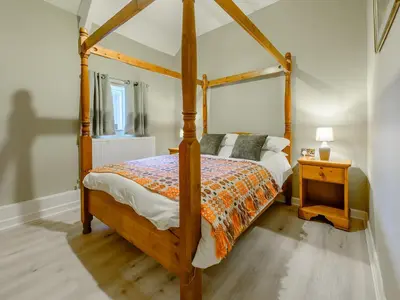 a bedroom with a canopy bed and a night stand at Maesyrhaf in Llanllwchaiarn