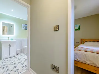 a bedroom with a bed and a bathroom with a mirror at Maesyrhaf in Llanllwchaiarn