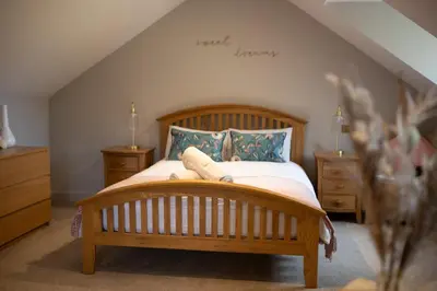 a bedroom with a wooden bed with pillows at Vineyard Country Cottage in Llanerch-Aeron