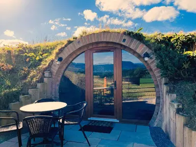 a patio with an archway with a table and chairs at Honeybee Home in Llansantffraid-ym-Mechain