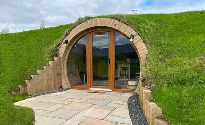 a stone archway with a glass door in a yard at Honeybee Home in Llansantffraid-ym-Mechain
