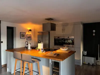 a kitchen with a wooden counter with two bar stools at Penestaer in Machynlleth