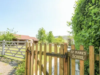 a wooden fence with a school sign on it at St Marks School House in Llanwrthwl
