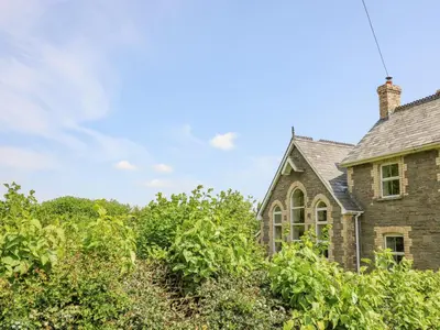 an old stone house surrounded by trees and bushes at St Marks School House in Llanwrthwl