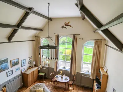 a living room with a table and two windows at St Marks School House in Llanwrthwl