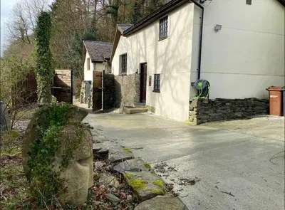 a house with a stone head next to a driveway at Coed Y Ddraig - themed 3 bedroom cottage, with bar & pool table in Tregaron