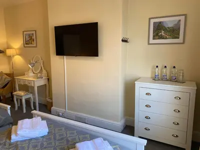 a room with a dresser and a flat screen tv at Brooklands Guest House in Llandrindod Wells