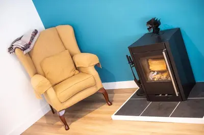 a living room with a chair and a fireplace at The Old Coach House in Aberaeron