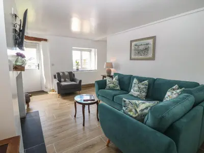 a living room with a green couch and a table at Yr Ysgubor in Dyffryn
