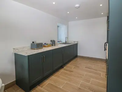 a kitchen with green cabinets and a counter top at Yr Ysgubor in Dyffryn
