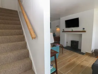 a living room with stairs and a living room with a fireplace at Yr Ysgubor in Dyffryn