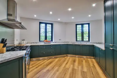 a large kitchen with green cabinets and wooden floors at Caer Beris Manor By Group Retreats in Builth Wells