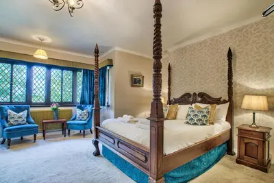 a bedroom with a four poster bed and blue chairs at Caer Beris Manor By Group Retreats in Builth Wells
