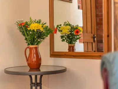 a vase of flowers on a table in front of a mirror at Hidden Gem in Stunning Location - Pass the Keys in Cressage