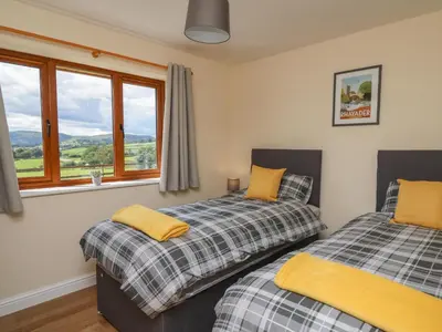 two beds in a room with a window at Awel y Bryn in Rhayader