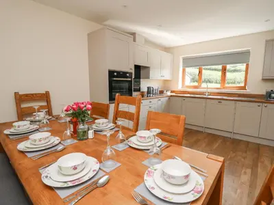 a kitchen and dining room with a wooden table with plates at Awel y Bryn in Rhayader