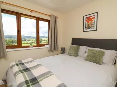 a bedroom with a bed with a large window at Awel y Bryn in Rhayader