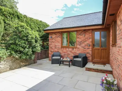 a brick house with two chairs and a table on a patio at Awel y Bryn in Rhayader