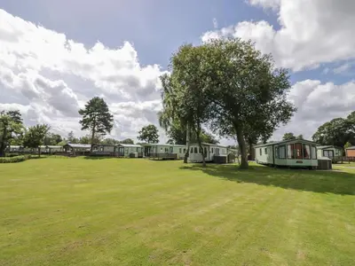 a group of mobile homes in a field with a tree at Heron in Leominster
