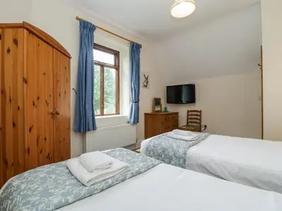 a bedroom with two beds and a tv and a window at Keepers Cottage in Leominster