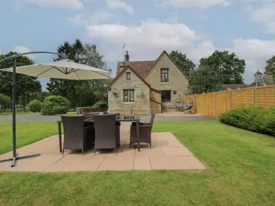 a patio with a table and chairs and an umbrella at Keepers Cottage in Leominster