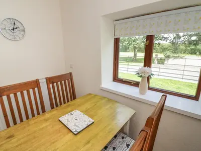 a dining room with a wooden table and a window at Stables Cottage in Leominster