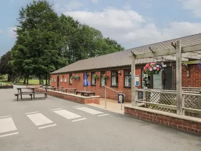 a red brick building with benches and flowers on it at Stables Cottage in Leominster
