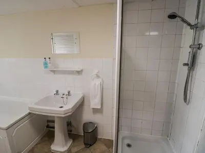 a white bathroom with a sink and a shower at Stables Cottage in Leominster