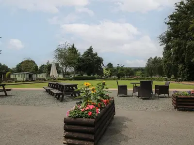 a park with picnic tables and chairs and flowers at Owl in Leominster