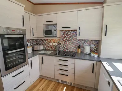 a kitchen with white cabinets and stainless steel appliances at Foxglove in Leominster