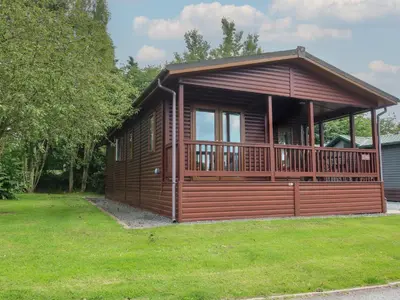 a large wooden cabin with a large deck at Daffodil in Leominster
