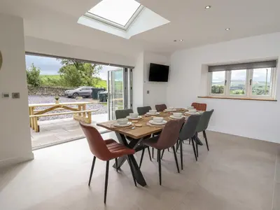 a dining room with a wooden table and chairs at Rhos Las in Derwen