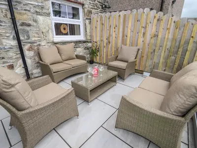 a patio with chairs and a table and a fence at Rhos Las in Derwen