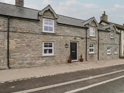 a stone building with a door on a street at Rhos Las in Derwen