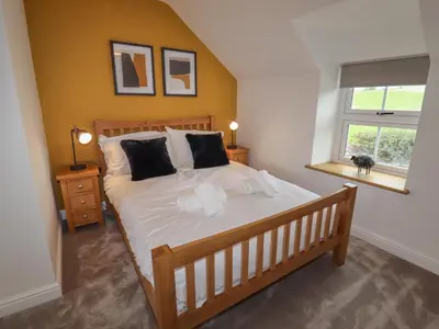 a bedroom with a bed with white sheets and a window at Rhos Las in Derwen
