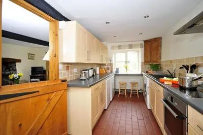 a kitchen with wooden cabinets and black counter tops at River Cottage Brecon: Hot Tub, Fire, Balcony, Wifi in Brecon