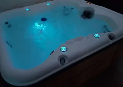 a white bath tub filled with blue water at River Cottage Brecon: Hot Tub, Fire, Balcony, Wifi in Brecon