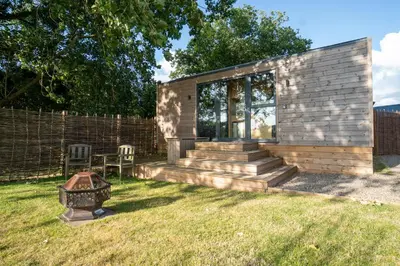a small house with glass doors and a yard at Beautiful cabins in Herefordshire countryside in Hereford