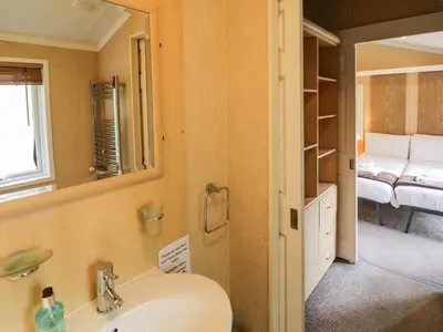 a bathroom with a sink and a mirror and a bedroom at Daisy in Leominster