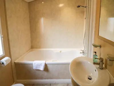 a bathroom with a bath tub and a sink at Daisy in Leominster