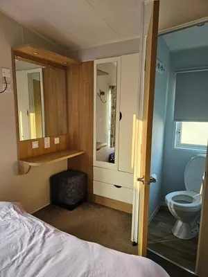 a bedroom with a bed and a toilet and a mirror at Caravan 4 - Cambrian Coast Caravan Park in Borth