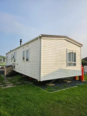 a small white trailer sitting in a yard at Caravan 4 - Cambrian Coast Caravan Park in Borth