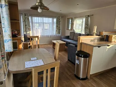 a kitchen and living room with a table and a couch at Caravan 4 - Cambrian Coast Caravan Park in Borth