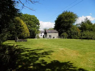 a large grass field with a house in the background at Converted Granary on a rural small holding in Cross Inn