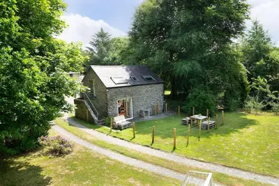 a small stone house in the middle of a yard at Converted Granary on a rural small holding in Cross Inn