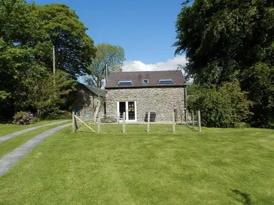 a stone house with a fence in front of a yard at Converted Granary on a rural small holding in Cross Inn