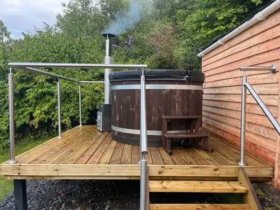 a hot tub sitting on a wooden deck at Erw Fair in Arthog
