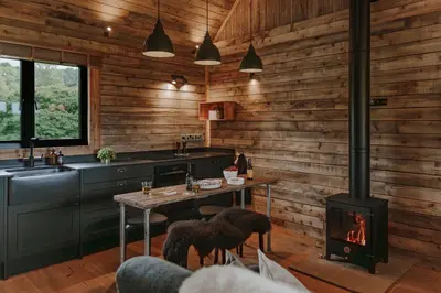 a kitchen with a stove and a table with chairs at Woolly Wood Cabins - Bryn in Llandrindod Wells